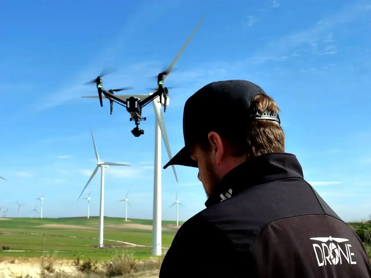 Piloto de dron junto a un parque eólico